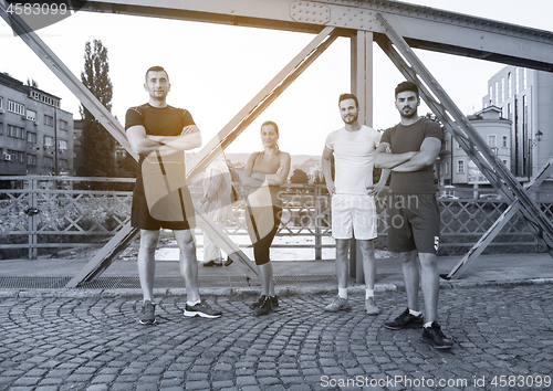 Image of group of young people jogging across the bridge