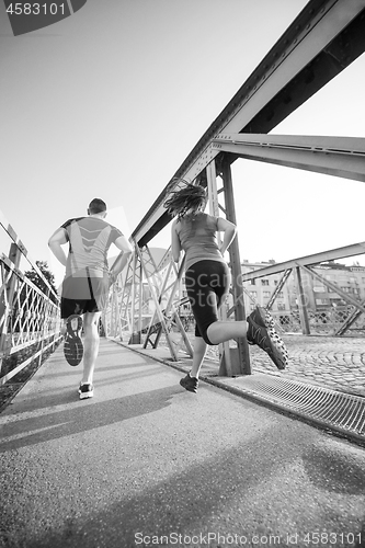 Image of young couple jogging across the bridge in the city