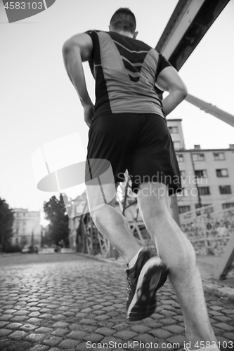 Image of man jogging across the bridge at sunny morning