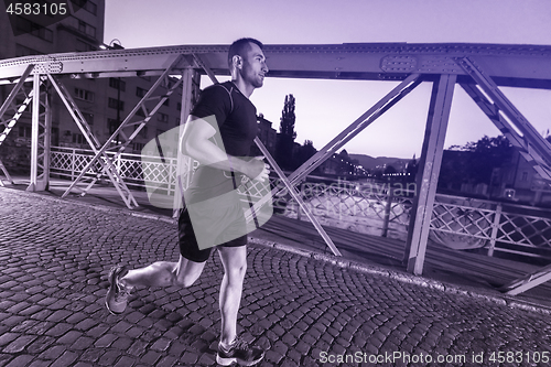 Image of man jogging across the bridge in the city