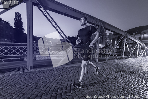 Image of man jogging across the bridge in the city