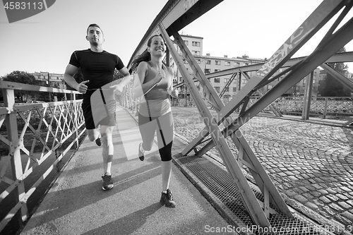 Image of young couple jogging across the bridge in the city