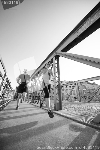 Image of young couple jogging across the bridge in the city