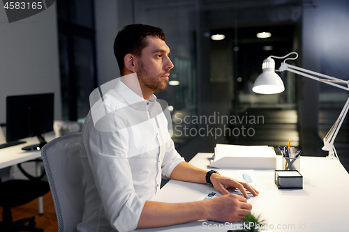 Image of businessman sitting at table at night office