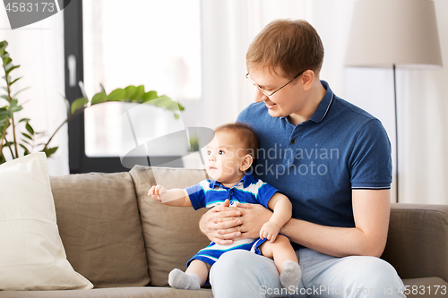 Image of happy father with baby son sitting on sofa at home