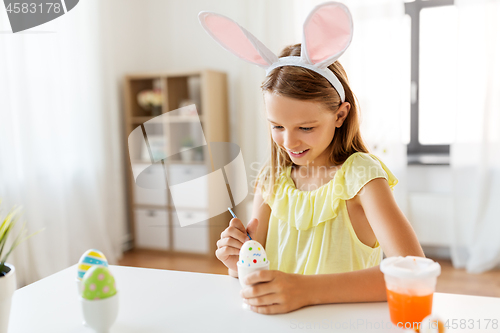 Image of happy girl coloring easter eggs at home