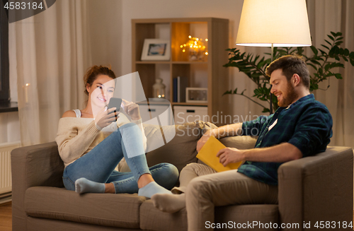 Image of couple with smartphone and book at home