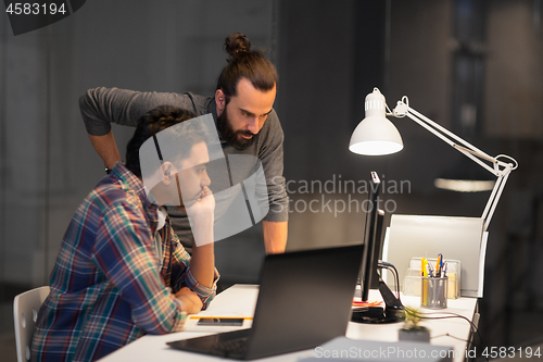 Image of creative team with computer working late at office