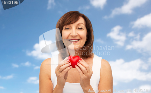 Image of portrait of smiling senior woman holding red heart