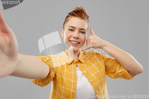 Image of teenage girl taking selfie making calling gesture