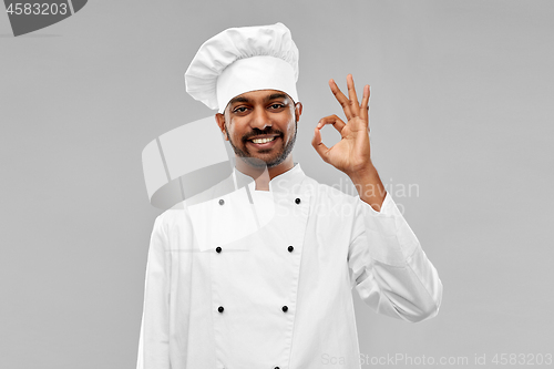 Image of happy male indian chef in toque showing ok gesture