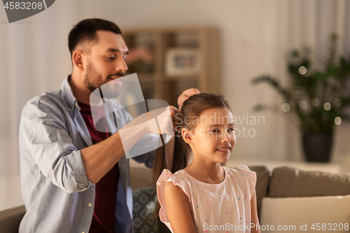 Image of father braiding daughter hair at home