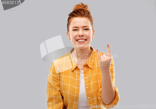 Image of happy red haired teenage girl showing rock gesture