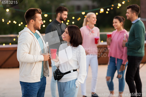 Image of friends with drinks in party cups at rooftop