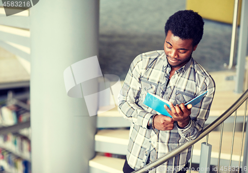 Image of african student boy or man reading book at library