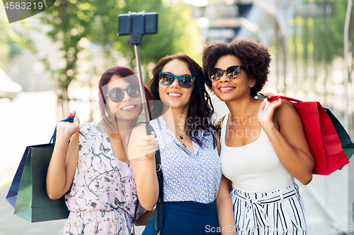 Image of women with shopping bags taking selfie outdoors