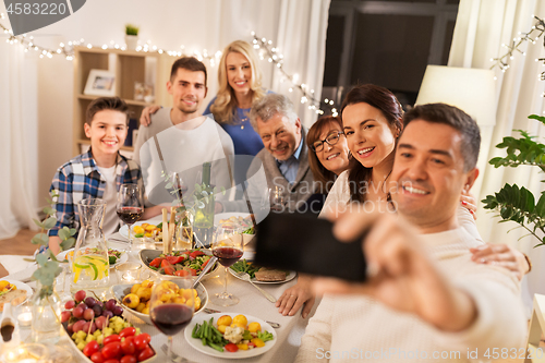 Image of family having dinner party and taking selfie