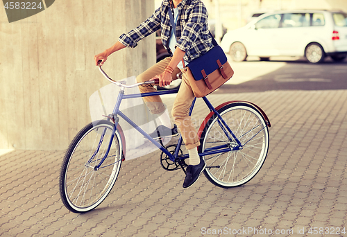 Image of young hipster man with bag riding fixed gear bike