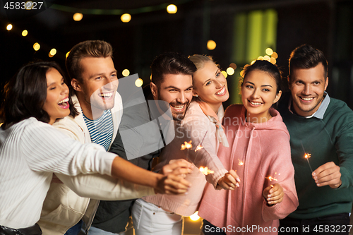 Image of happy friends with sparklers at rooftop party