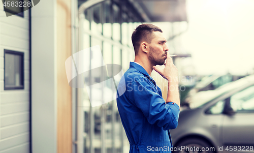 Image of auto mechanic smoking cigarette at car workshop