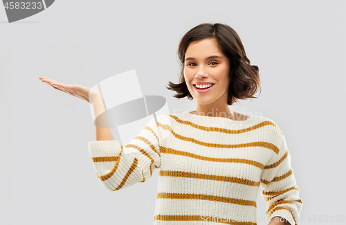 Image of smiling young woman holding empty palm