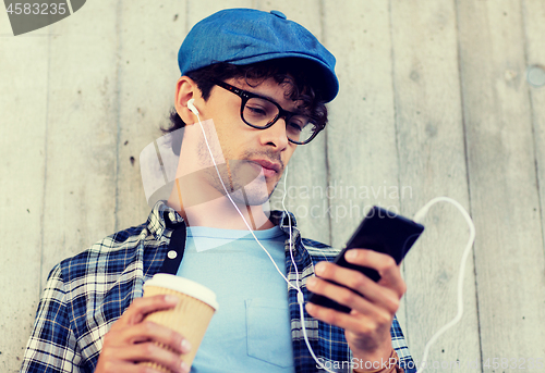 Image of man with earphones and smartphone drinking coffee