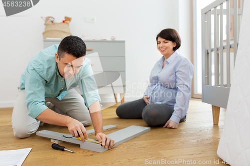 Image of family couple assembling baby bed at home