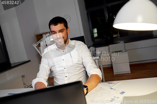 Image of businessman with laptop working at night office