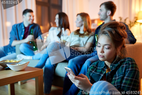 Image of sad young woman with smartphone at home party