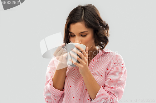 Image of young woman in pajama drinking coffee from mug