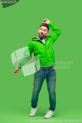 Image of handsome bearded young man looking at camera isolated on green