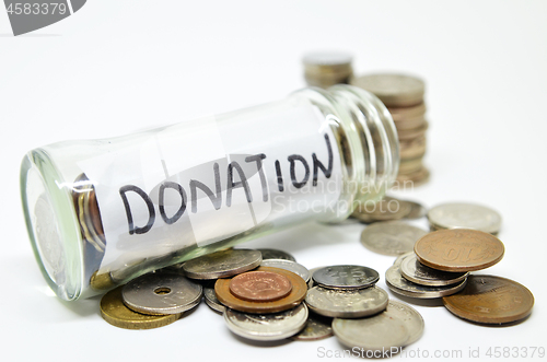 Image of Donation lable in a glass jar with coins spilling out