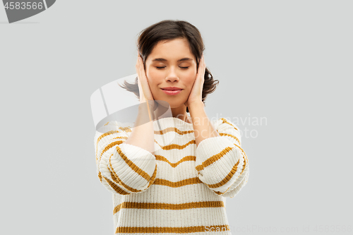 Image of happy woman in pullover closing ears by hands