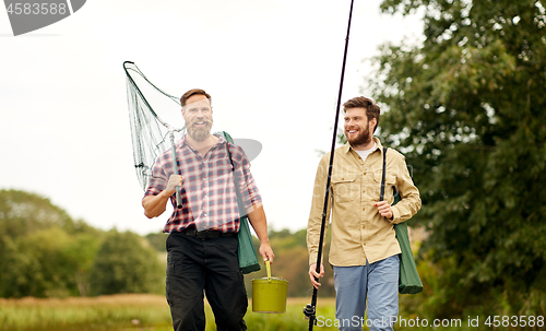 Image of friends with fishing rods and net walking outdoors