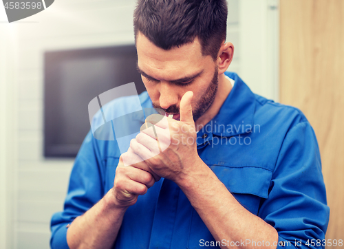 Image of auto mechanic smoking cigarette at car workshop