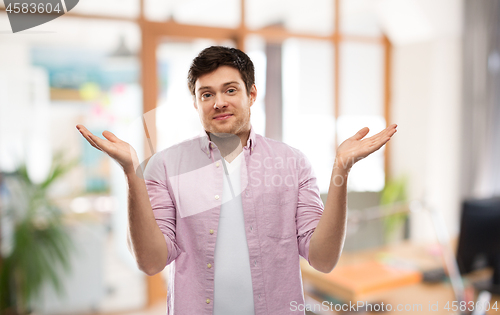 Image of young man shrugging over office room
