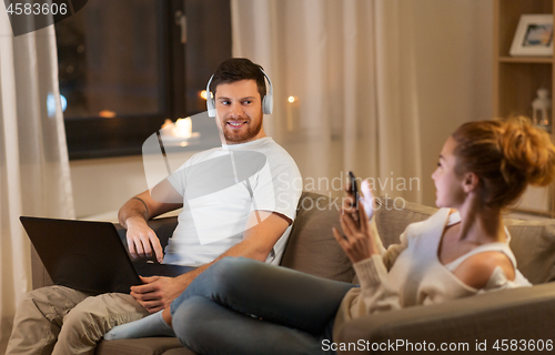 Image of couple with laptop and smartphone resting at home