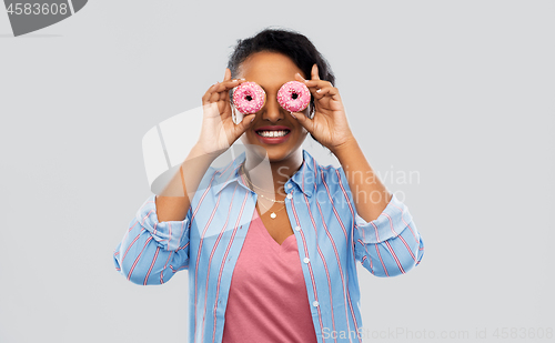 Image of happy african american woman with eyes of donuts