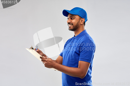 Image of happy indian delivery man with clipboard in blue