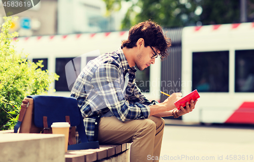 Image of man with notebook or diary writing on city street