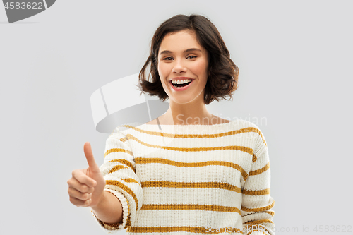 Image of smiling woman in pullover showing thumbs up