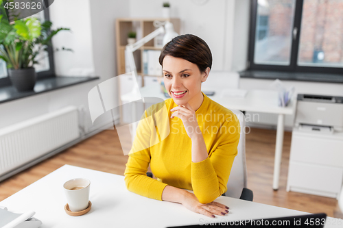 Image of happy businesswoman sitting at office table