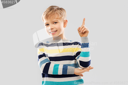 Image of little boy in striped pullover pointing finger up