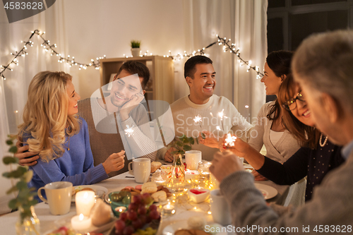 Image of family with sparklers having dinner party at home