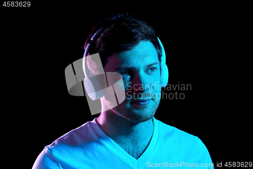 Image of man in headphones over neon lights of night club