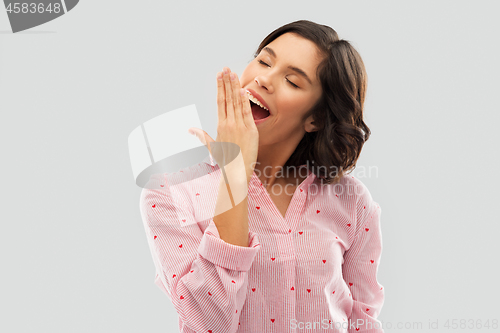 Image of happy young sleepy woman in pajama yawning