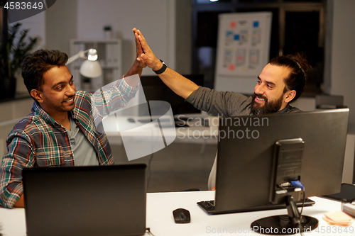 Image of creative team making high five at night office