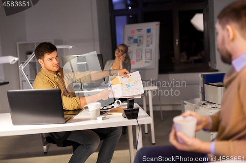 Image of business team with papers working late at office