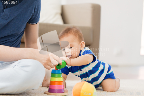 Image of baby boy with father and pyramid toy at home