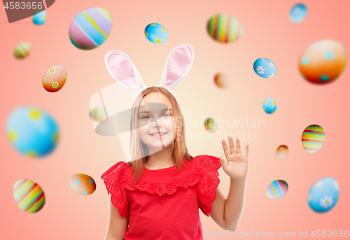 Image of happy girl wearing easter bunny ears waving hand